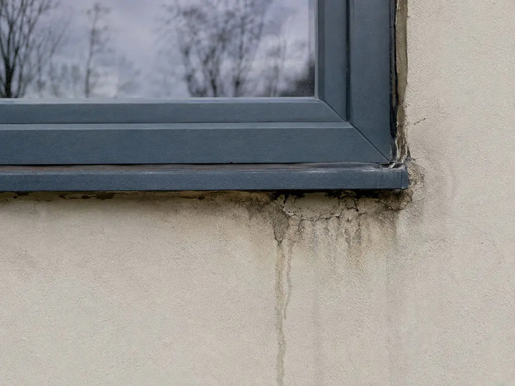 Joint de menuiserie dégradé et traces d'infiltration sous une fenêtre