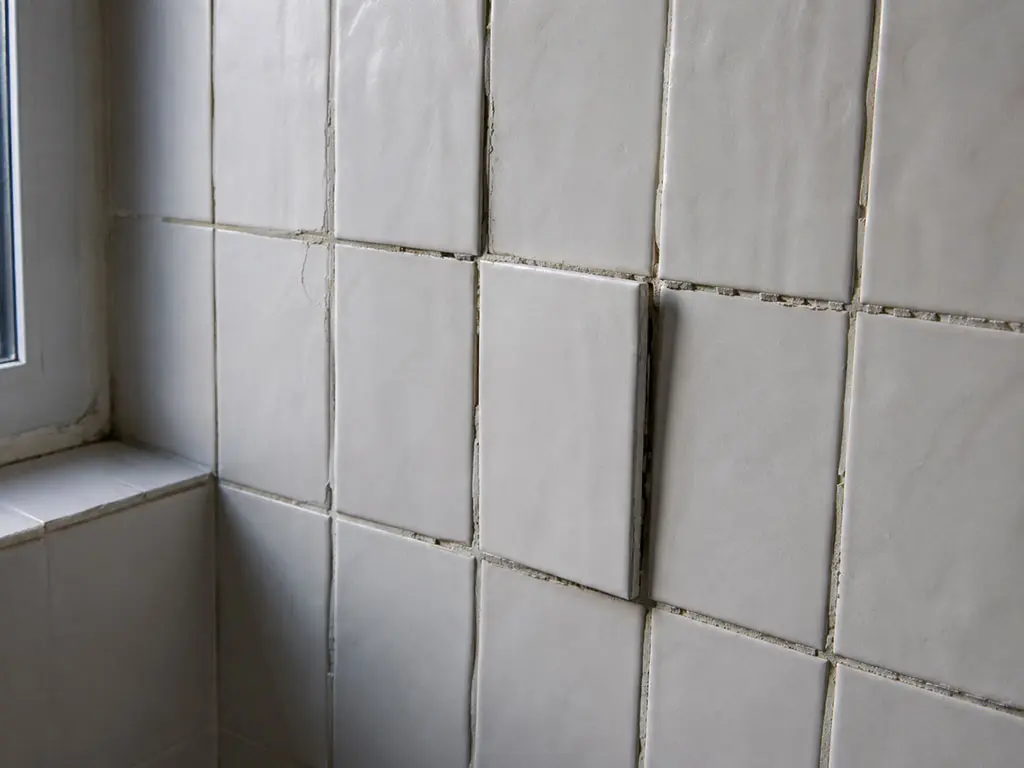 Malfaçon de finition : carrelage irrégulier et joints grossiers